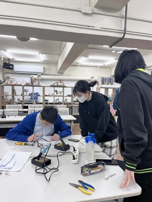 學生互相觀摩彼此指導電烙鐵的使用方式圖片