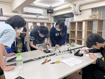 學生互相觀摩彼此指導電烙鐵的使用方式圖片