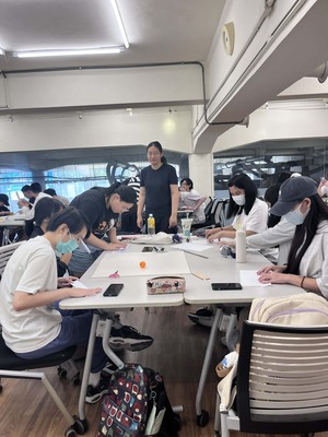 學生動手摺紙、黏貼膠帶製作軌道的特寫，展現「先做再說」的動手精神圖片